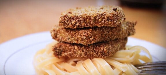 Three slabs of pistachio crusted tofu stacked on pasta.