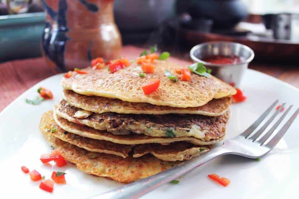 completed stack of potato leek hash brown pancakes on a white plate