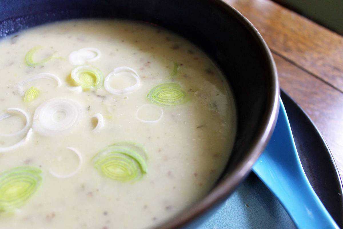Closeup of a brown bowl filled with potato leek soup.