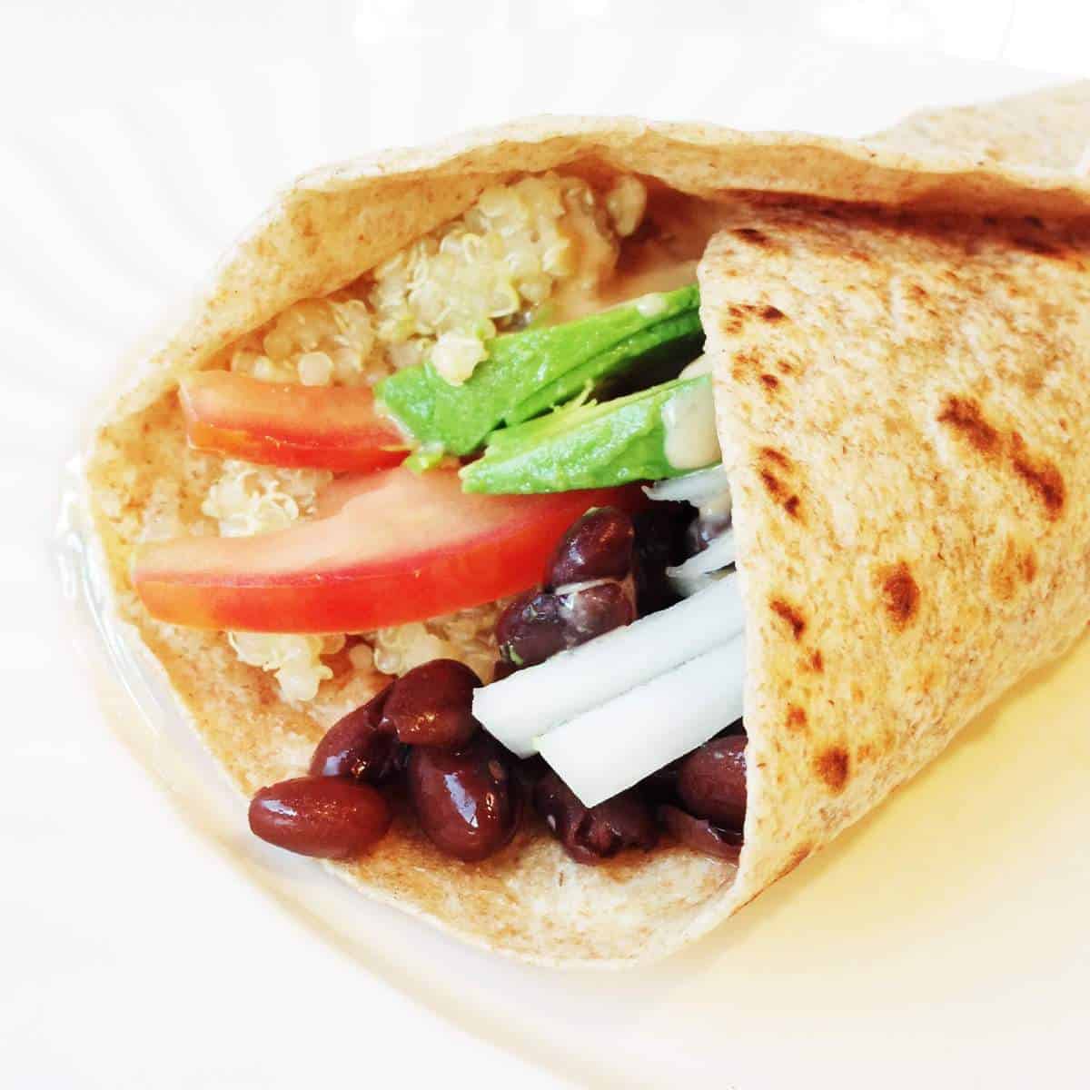 Close up of the filling of a quinoa burrito on a white background.