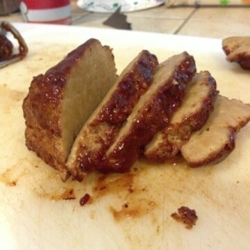 Smoked seitan in slices on a cutting board.