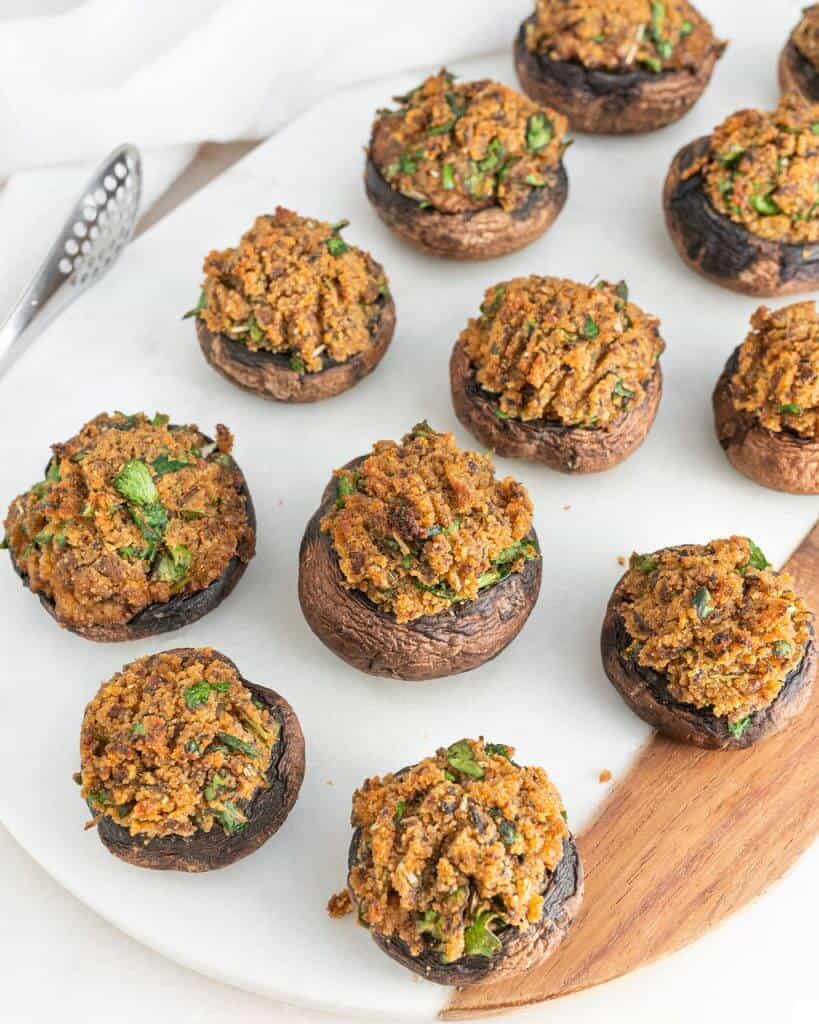 several finished stuffed mushrooms on a white serving platter