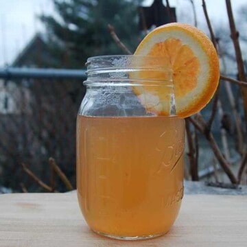 A Mason jar of wonder tonic with an orange slice on the rim.