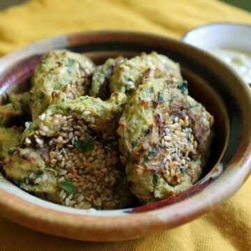 Sesame zucchini fritters in a small brown bowl.