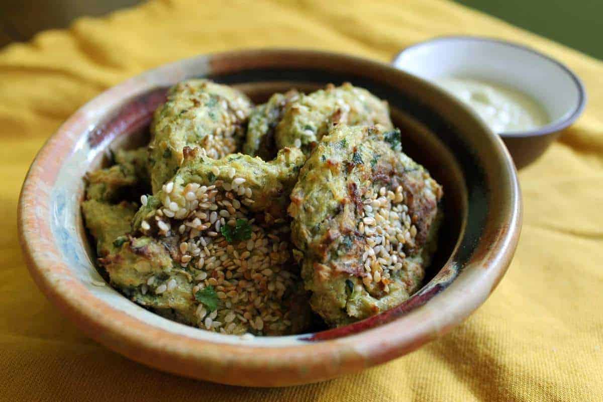 Sesame zucchini fritters in a small brown bowl.
