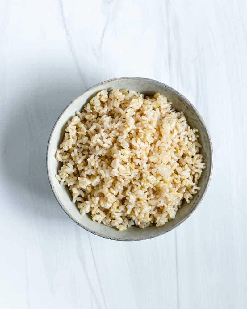 Bowl of Cooked Brown Rice on a White Marble Surface