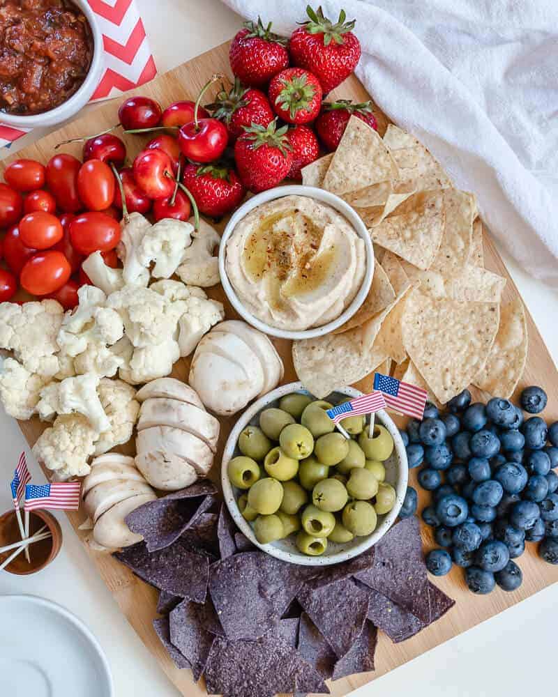 colorful charcuterie board with chips, olives and tomatoes