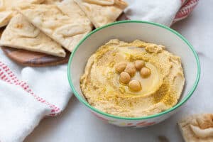 finished Classic Hummus in a white bowl with chips in the background