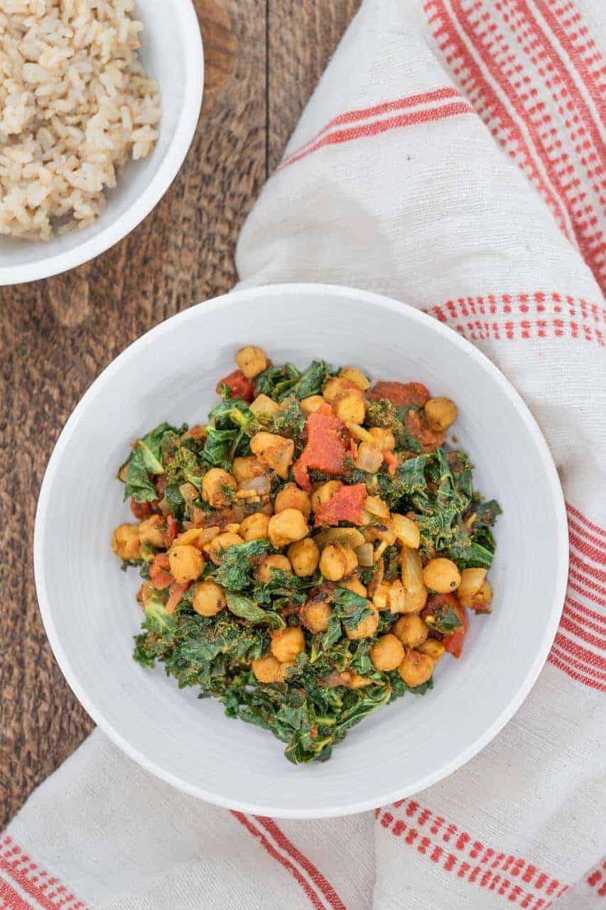 Curried chickpeas and kale in a white bowl.
