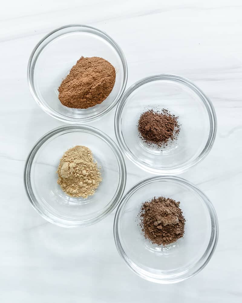 pumpkin spice ingredients in four glass jars with a white background