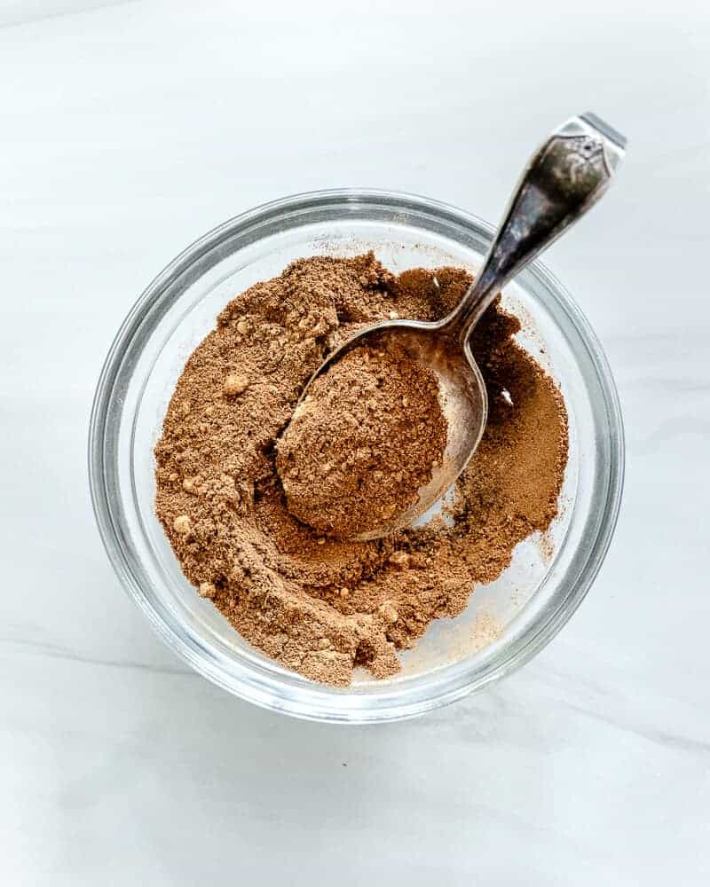 pumpkin pie spice in glass bowl with a white marble background