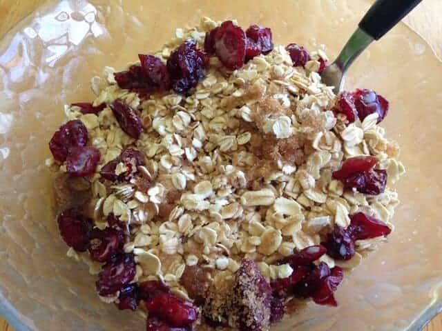 Oatmeal, dried cranberries, and soymilk in a glass bowl.