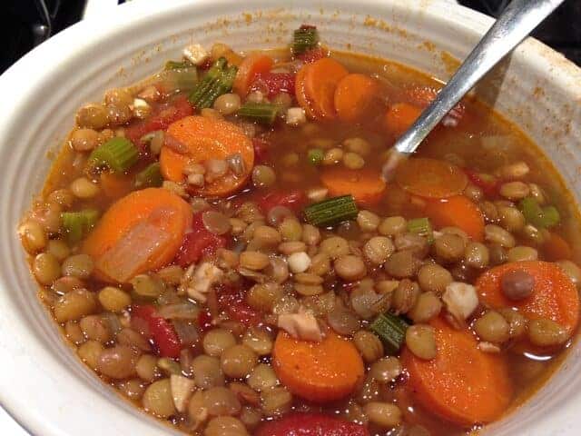 Lentil veggie soup and a spoon in a white bowl.