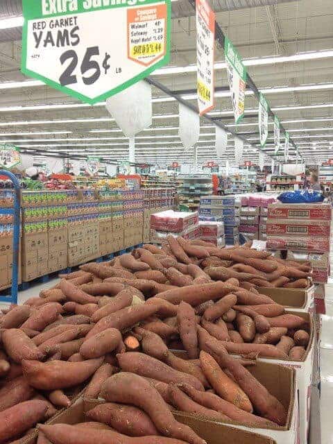 Crates of yams in a grocery store produce aisle.