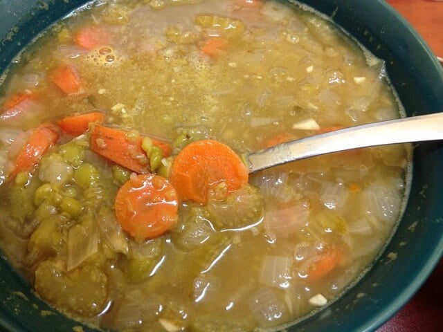 A bowl full of split pea soup that also has carrots, celery, and onion.