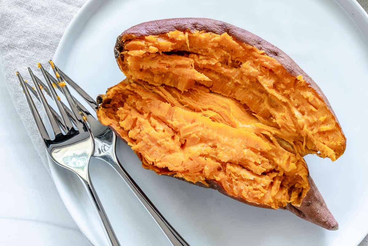sweet potato cut in half on white plate against white background