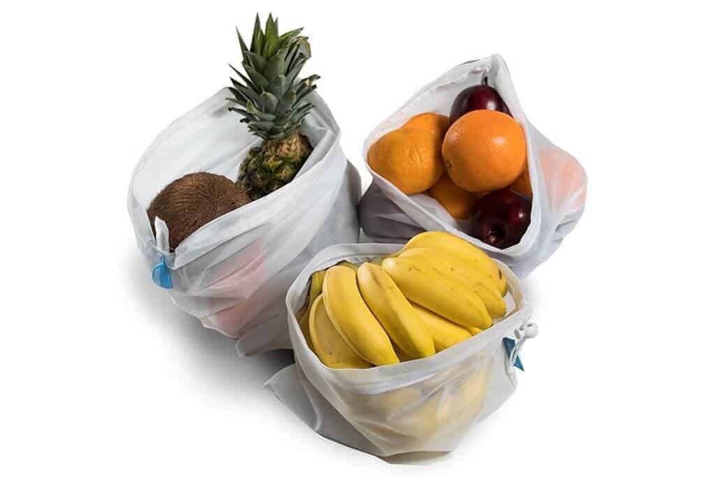 Apples, oranges, and bananas in reusable mesh produce bags.