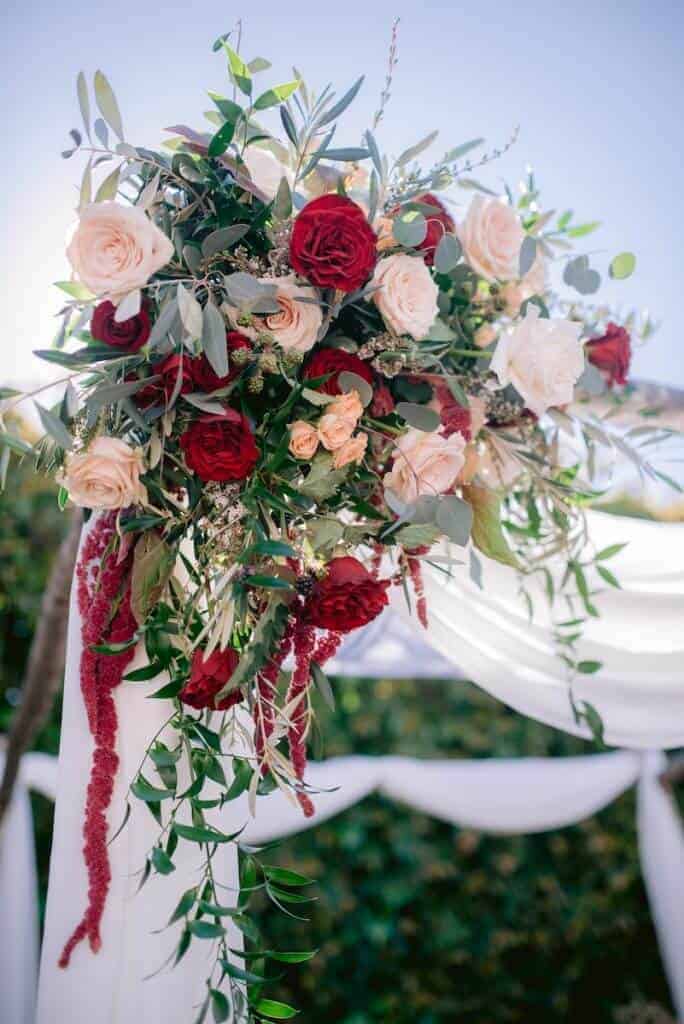 Flower bouquet at the top of a white wedding chuppah.