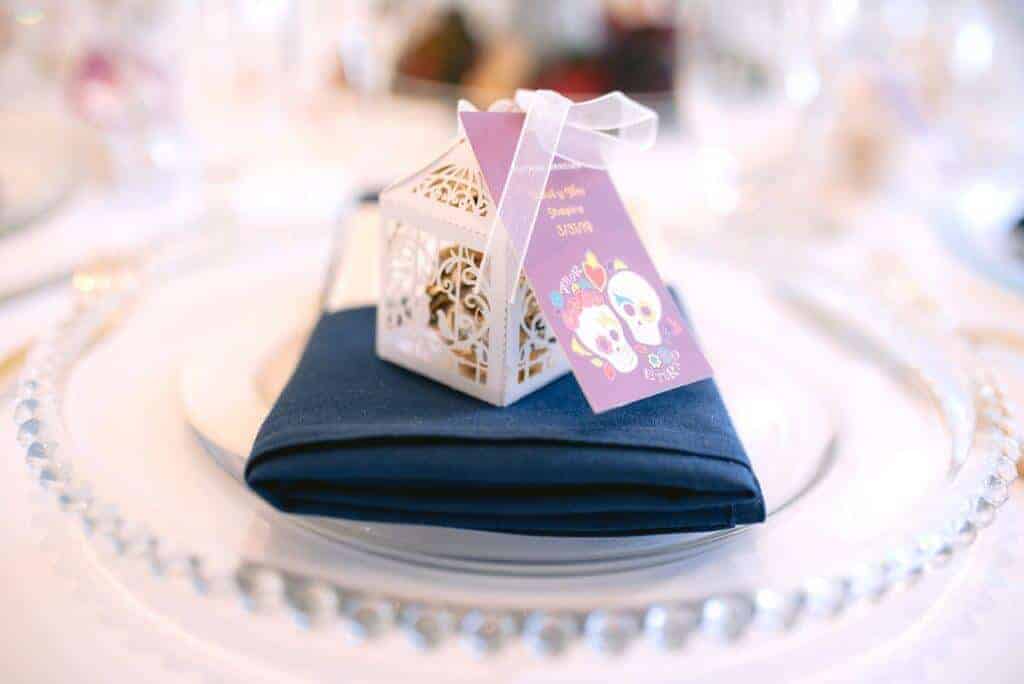 Wedding favor box on top of a navy napkin on a glass plate.