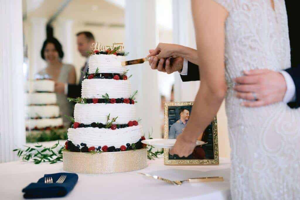 Bride and groom slicing a white layered cake.