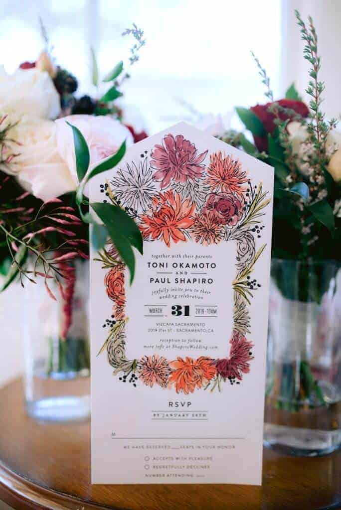 Wedding invitation leaning against a flower vase.