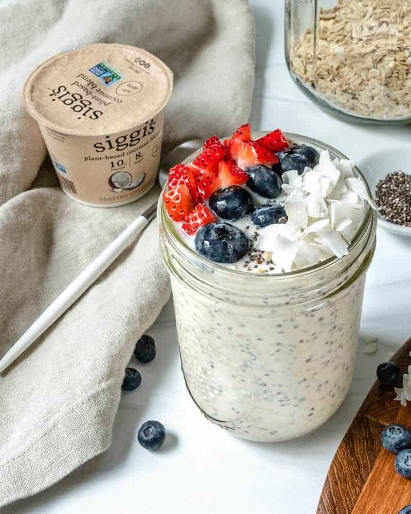 overnight oats in glass jar with fruit on top in a white background