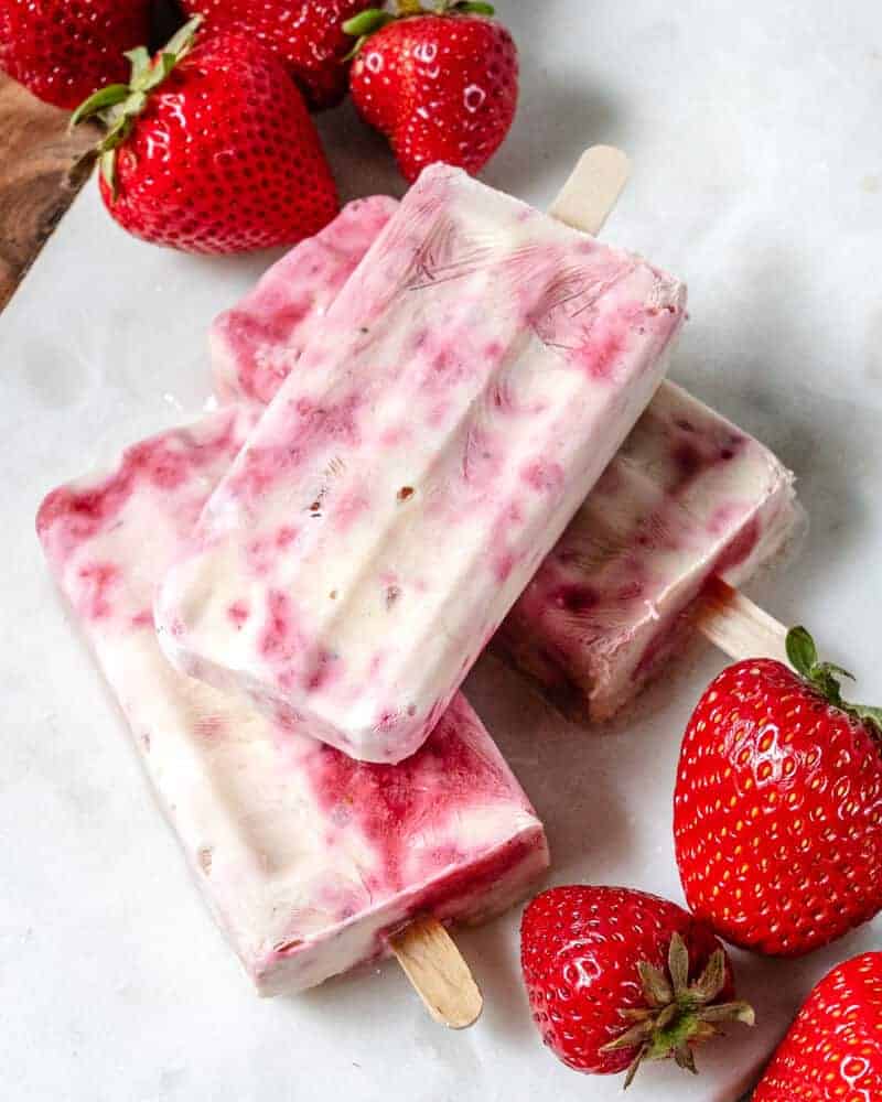 plate of strawberry popsicles with strawberries in the background