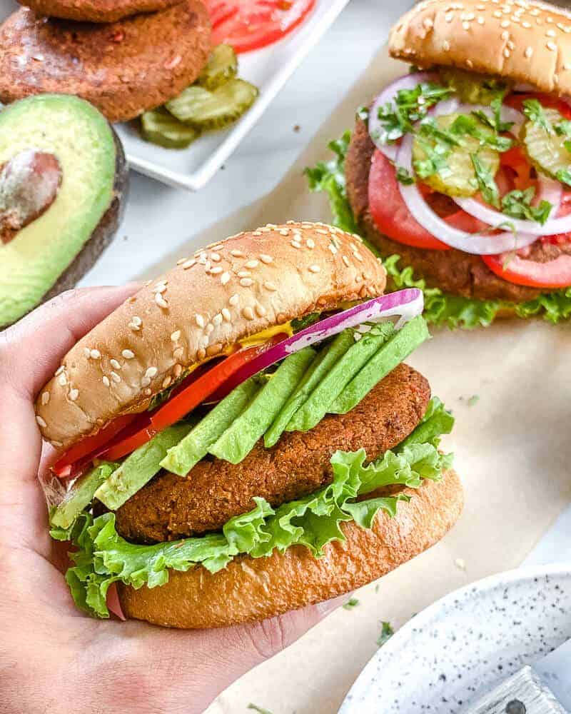 hand holding a southwest black bean burger with all the fixins on a bun.