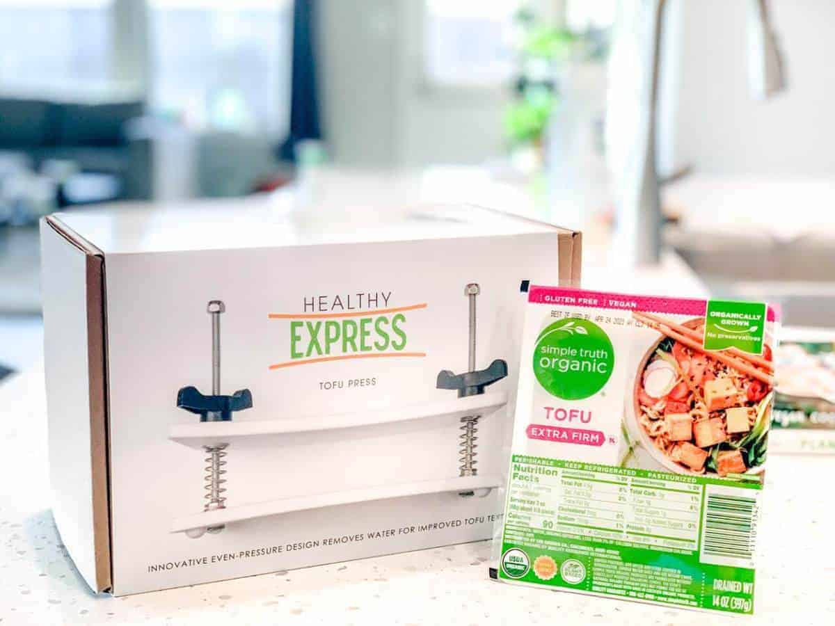 Tofu Press by healthy Express with a block of packaged tofu on a kitchen counter