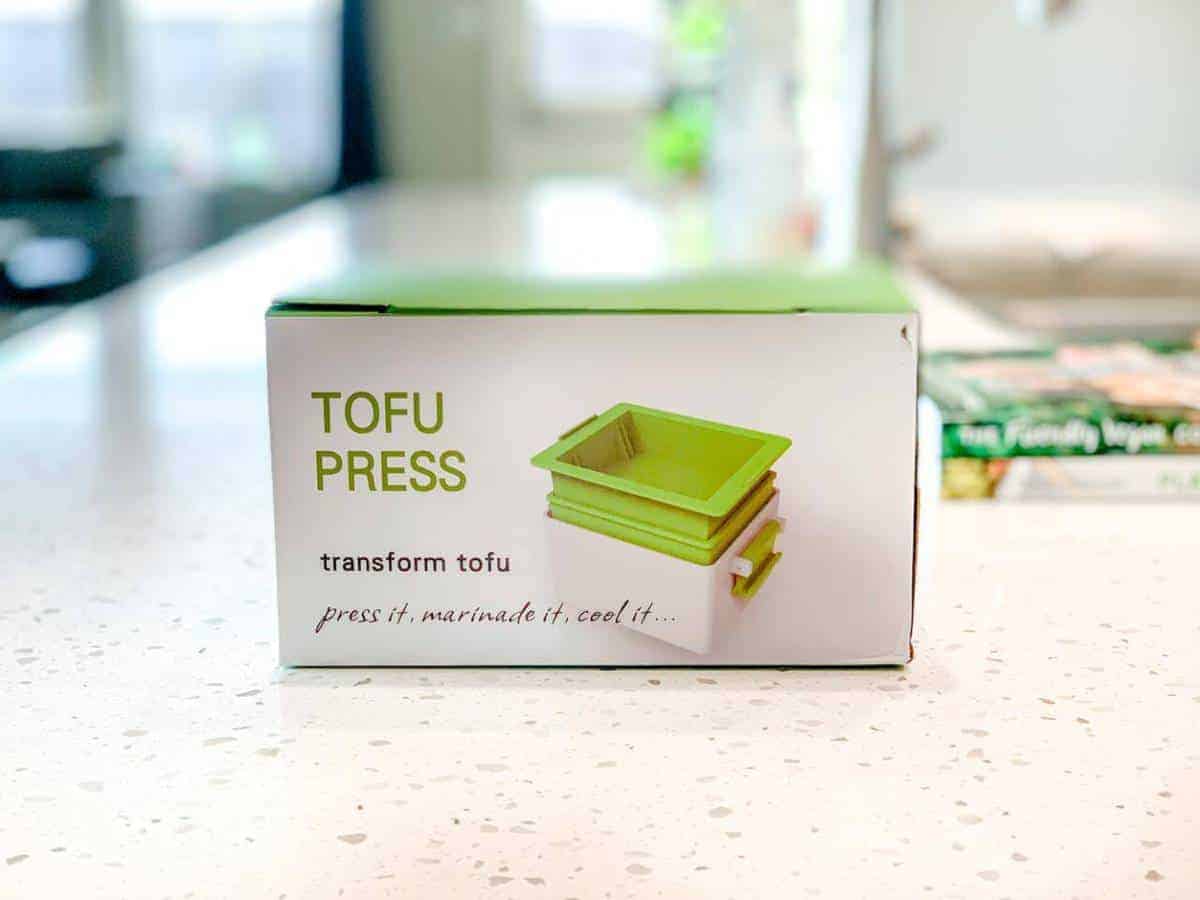 Tofu press in a box on a marble counter.