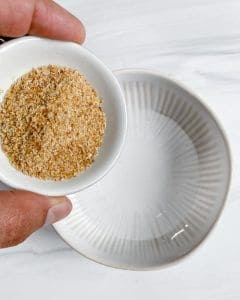 preparation of flax seed into bowl of water against a white background