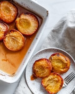 roasted peaches in a white dish and plate with a white background