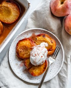 roasted peaches in white dish and plate with ice cream on top in a white background