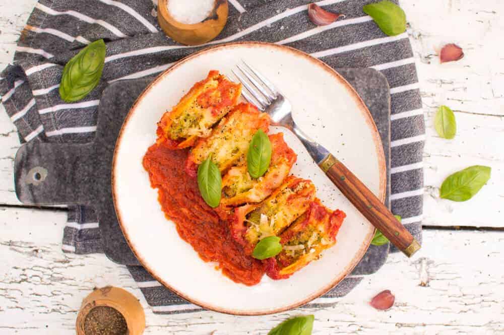 cooked vegan stuffed shells plated on a white plate with a gray and white stripped towel in the background