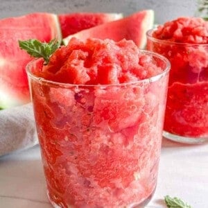 completed Watermelon Slushi in two glasses with watermelon in the background