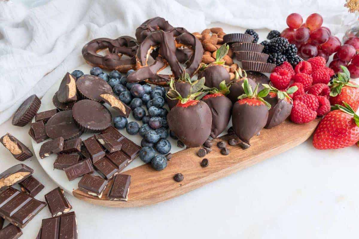 Board with chocolate pretzels, peanut butter buts and a variety of berries