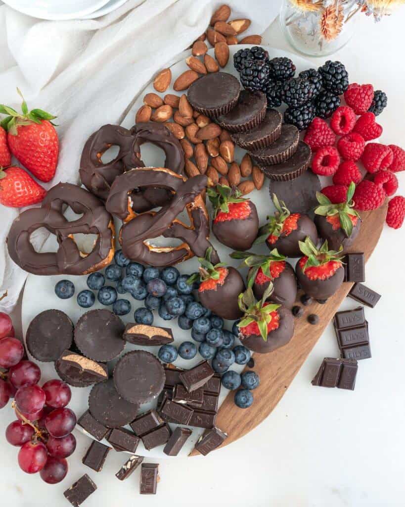 completed charcuterie board with a wide array of fruits and chocolate on a board