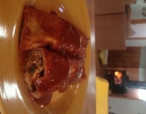 Enchiladas and refried beans on a dinner plate.