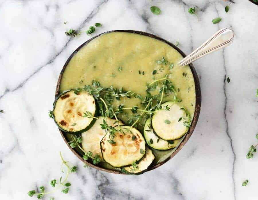 one dark bowl with zucchini soup in a marble background