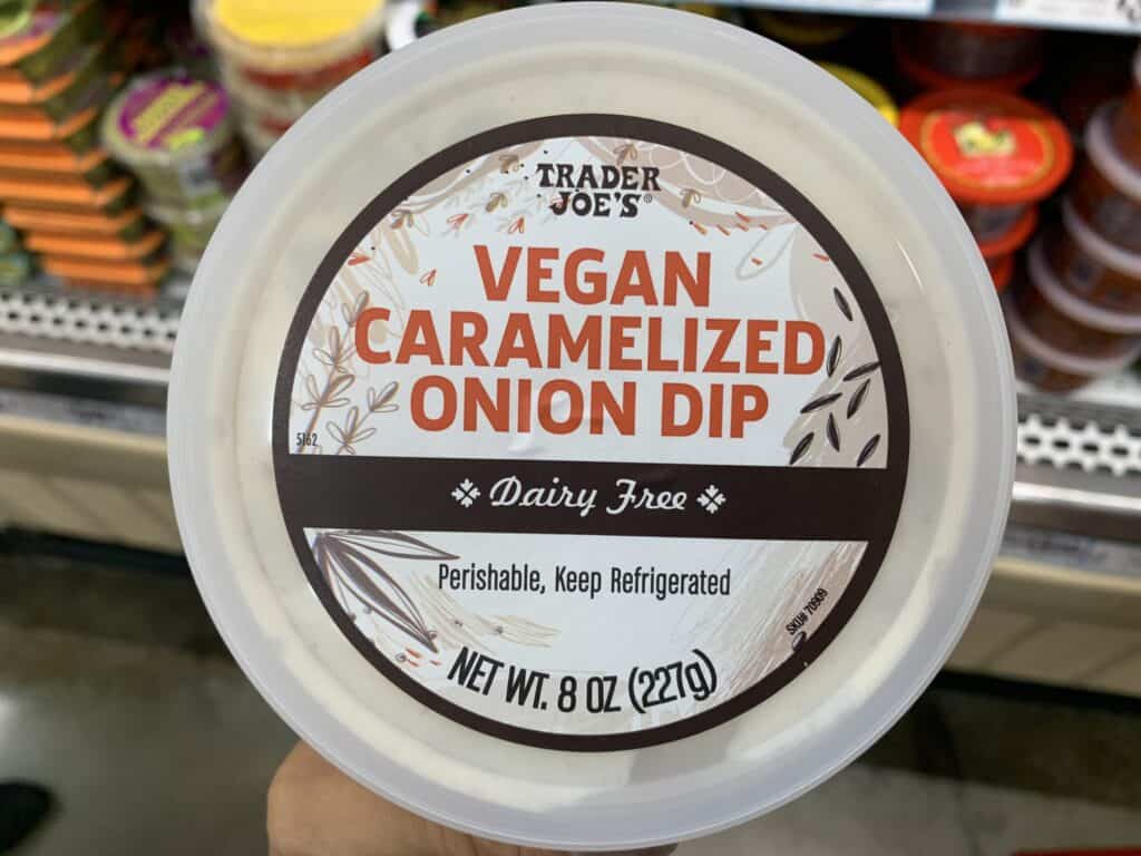 packaged vegan varamelized onion dip against a dark background