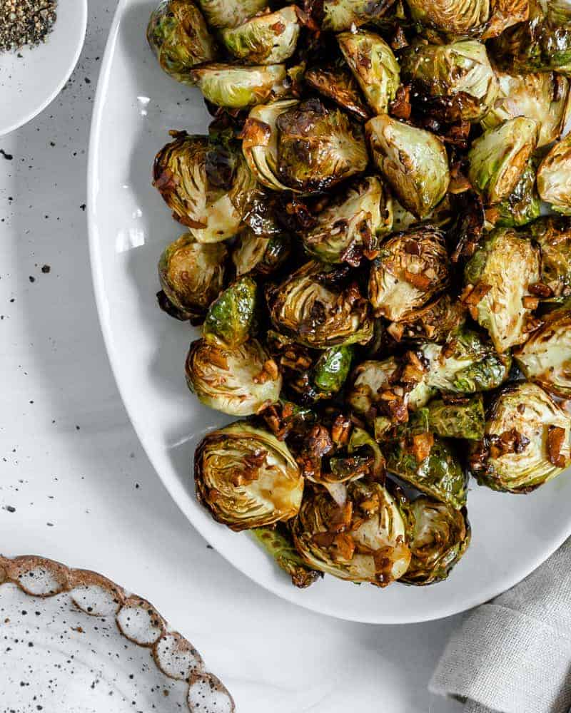 finished Crispy Air Fryer Brussels Sprouts plated on a white dish against a white background