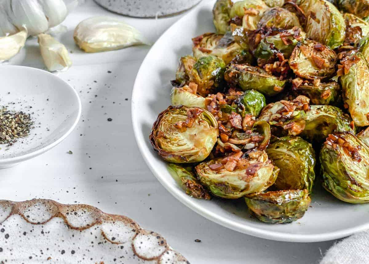 finished Crispy Air Fryer Brussels Sprouts plated on a white dish against a white background 