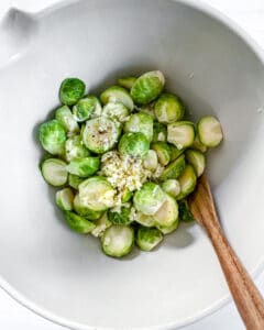 brussels sprouts in a white bowl with a wooden spoon