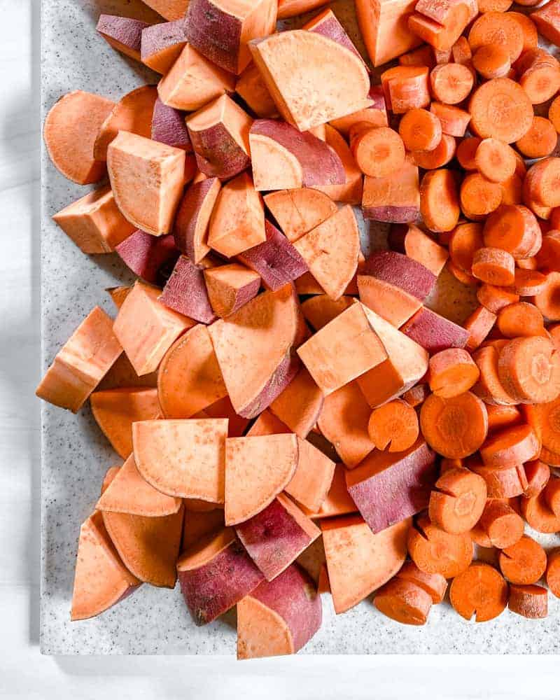 raw Yams and Carrots Sliced against a white surface