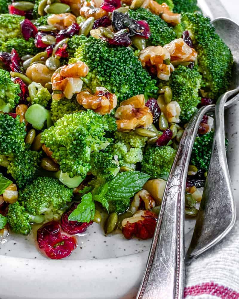 Vegan Broccoli Salad in a white dish with two spoons 
