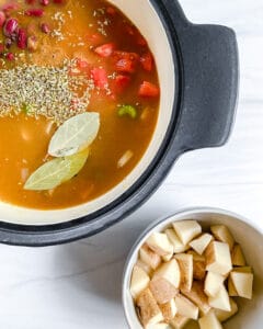 process of cooking Vegan Minestrone Soup in pot with ingredients on the side