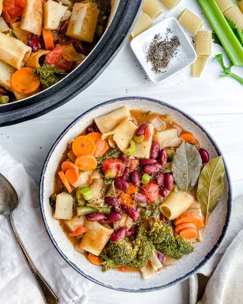 completed Vegan Minestrone Soup in a white bowl and additional soup in the background