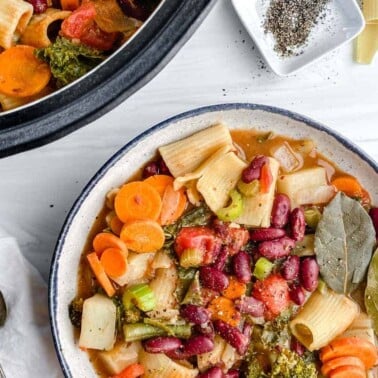 completed Vegan Minestrone Soup in a white bowl and additional soup in the background
