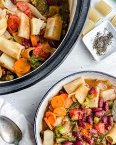completed Vegan Minestrone Soup in a white bowl and additional soup in the background