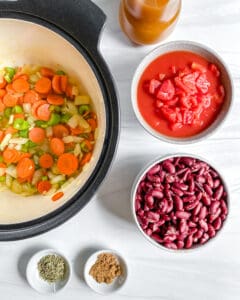 process of cooking Vegan Minestrone Soup in pot with ingredients on the side